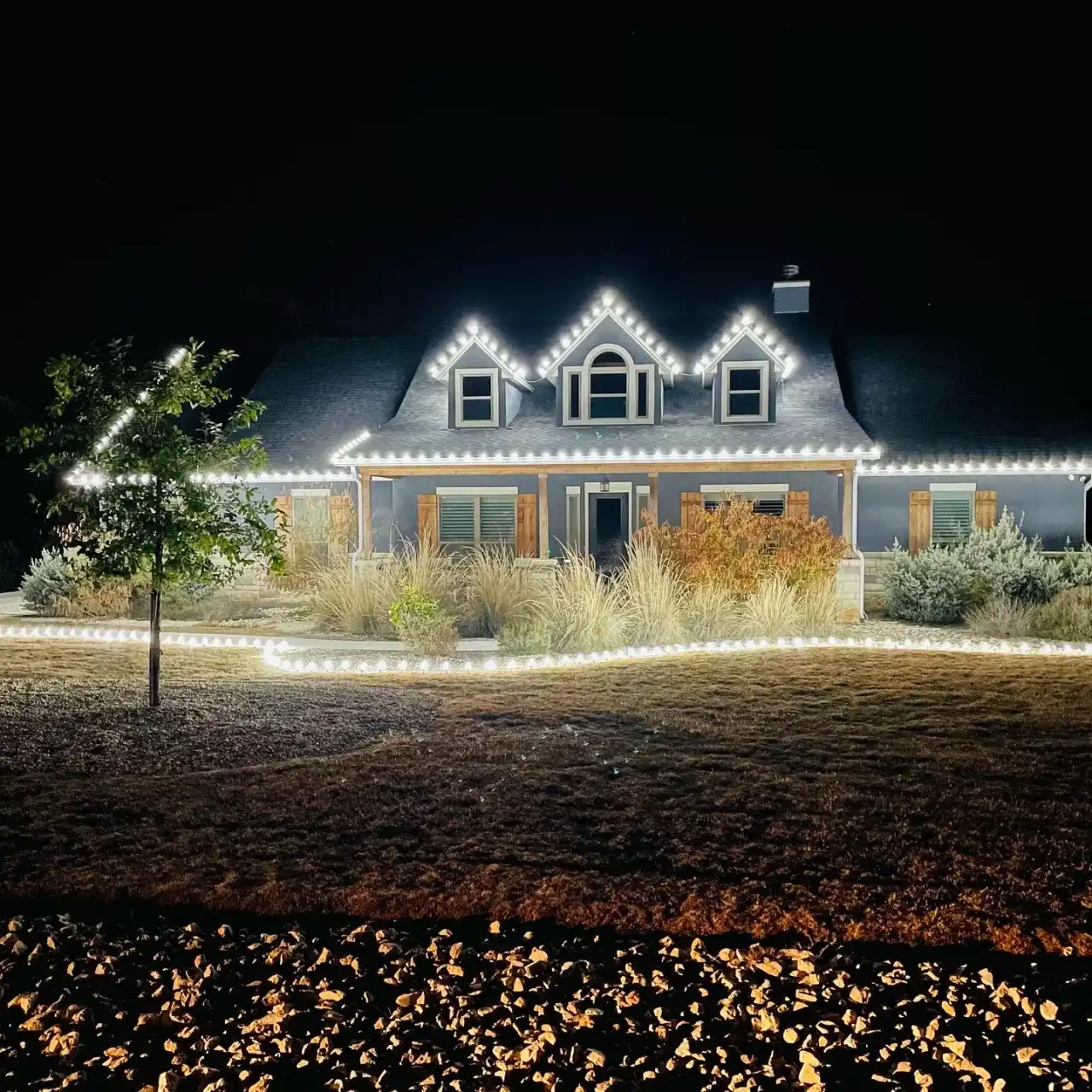 Home with warm white roofline lights and a lit pathway at night